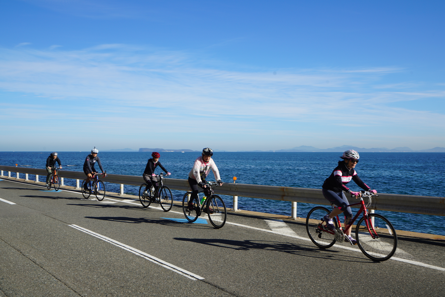 車隊沿九州濱海道路一字排開騎乘,右側為藍色大海