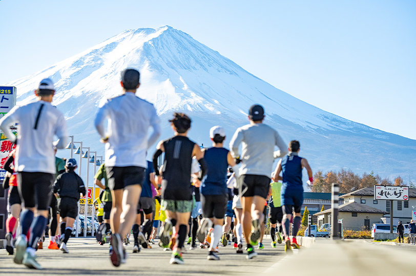 富士山馬拉松跑者穿著長袖長褲、帽子等冬季裝備，朝雪頂富士山方向奔跑